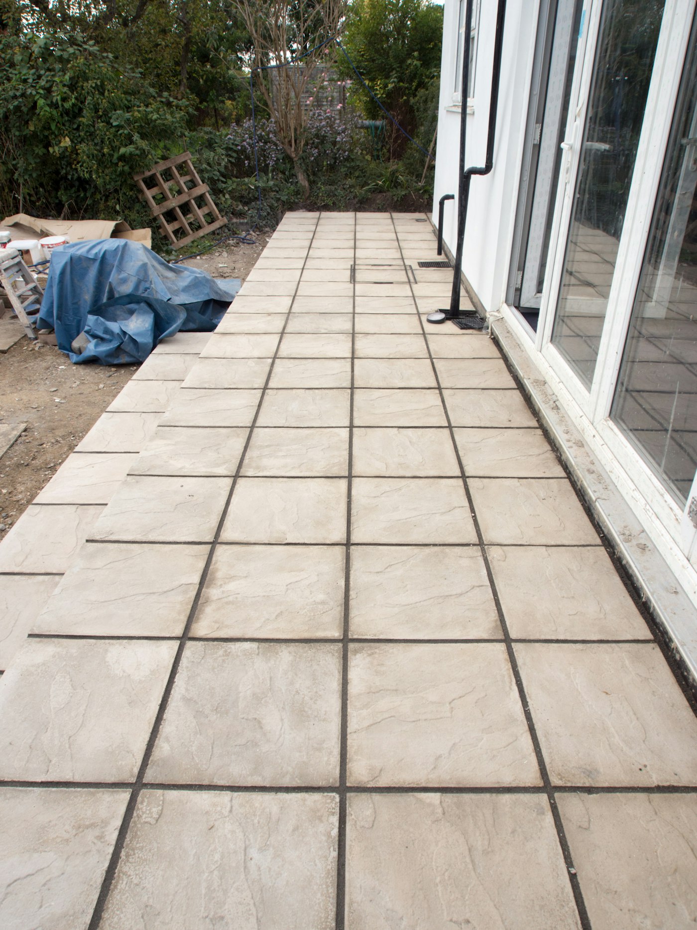 Nieuw gelegde terrastegels langs een woning tijdens de tuinaanleg
